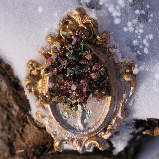 Close-up of a wire-wrapped tourmaline gemstone Tree of Life in an ornate Baroque-style frame