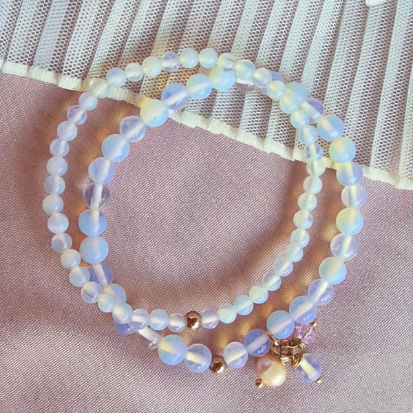 A luminous moonstone pendant glowing against a dark velvet background, surrounded by scattered moonstones and silver accents
