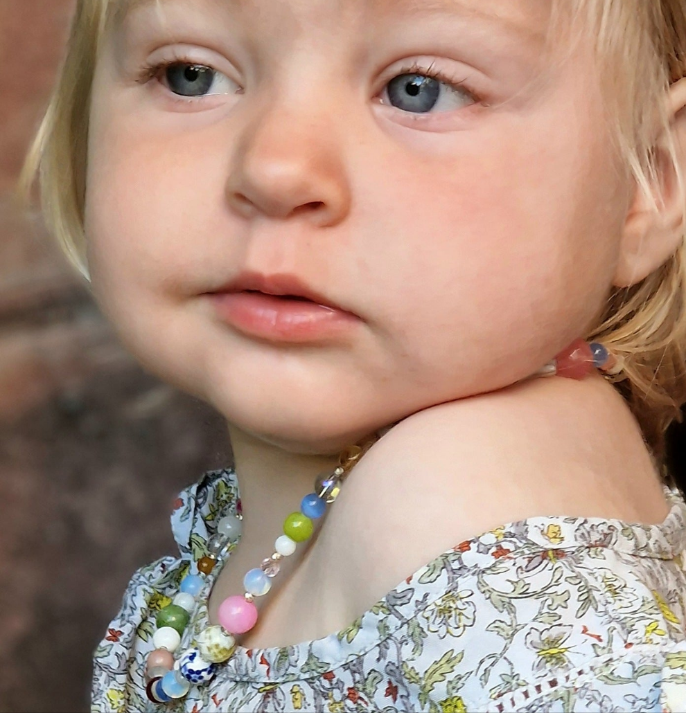Side view of a blonde-haired girl showcasing the 45 cm gemstone necklace on elastic cord, accented by mother-of-pearl and moonstone beads