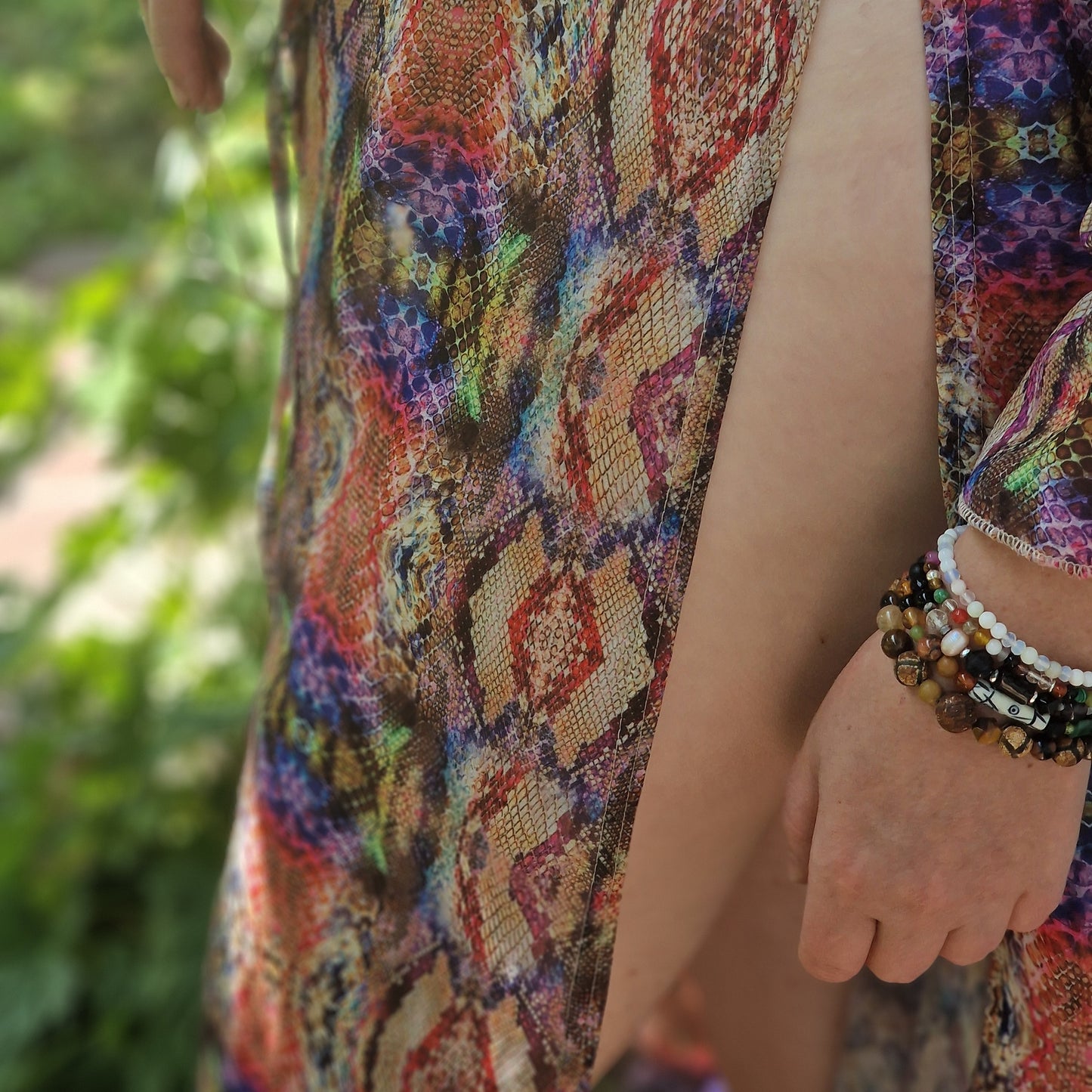 Side view of the Emerald & African Element bracelet on a slender wrist, highlighting green emerald, peridot, tiger’s eye, onyx and a handcrafted Lesotho charm