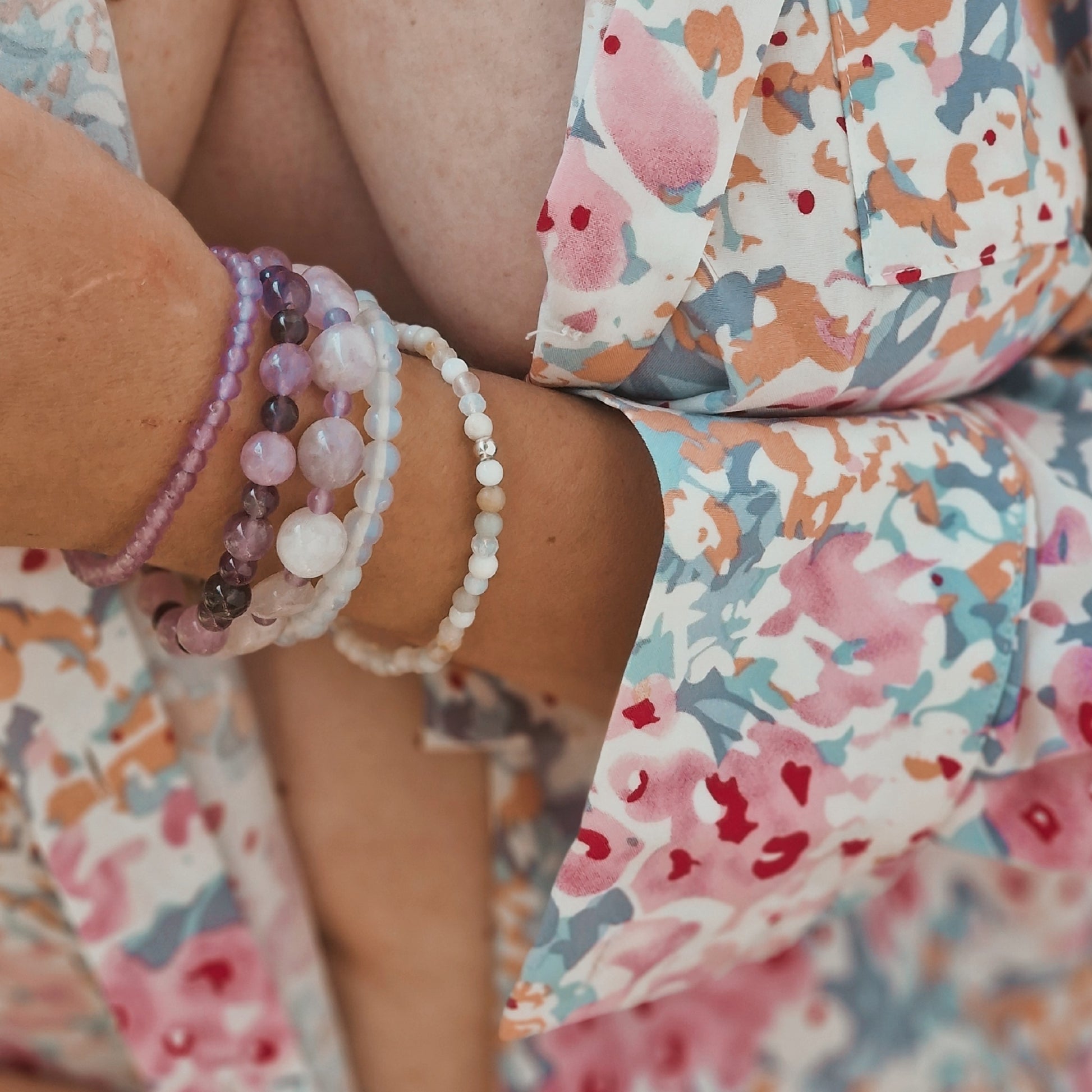 Beautifully layered gemstone bracelets on a female wrist, showcasing the rare energy of jade, amethyst, moonstone and mixed stones