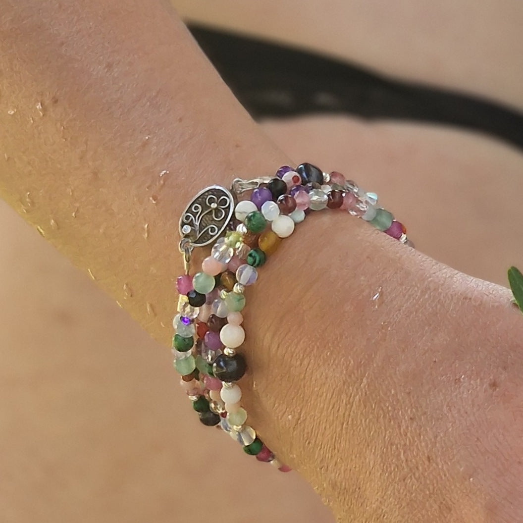 A 90 cm five-wrap gemstone wrap bracelet featuring agate, amethyst, rose quartz, tourmaline, jadeite and other healing stones, worn on a woman’s wrist with sterling silver clasp