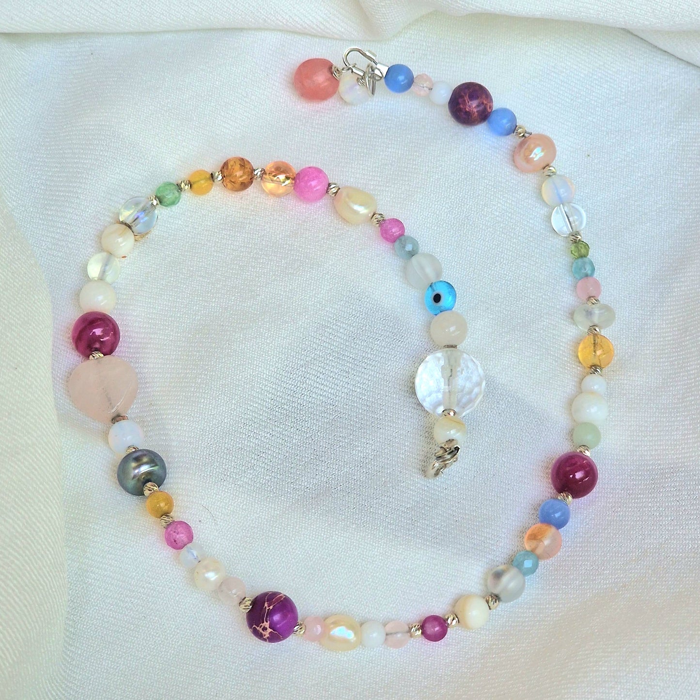 A delicate 45 cm girls’ gemstone necklace named Leonor, showcasing freshwater pearls, agate, rose quartz, clear quartz, moonstone, and tourmaline with a sterling silver clasp on a neutral background