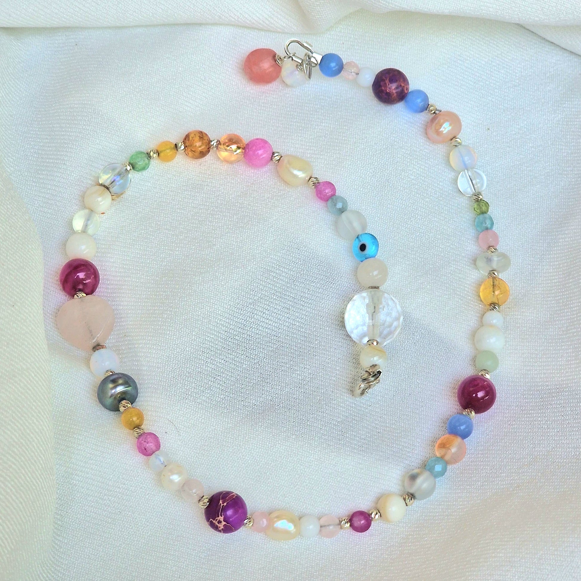 A delicate 45 cm girls’ gemstone necklace named Leonor, showcasing freshwater pearls, agate, rose quartz, clear quartz, moonstone, and tourmaline with a sterling silver clasp on a neutral background