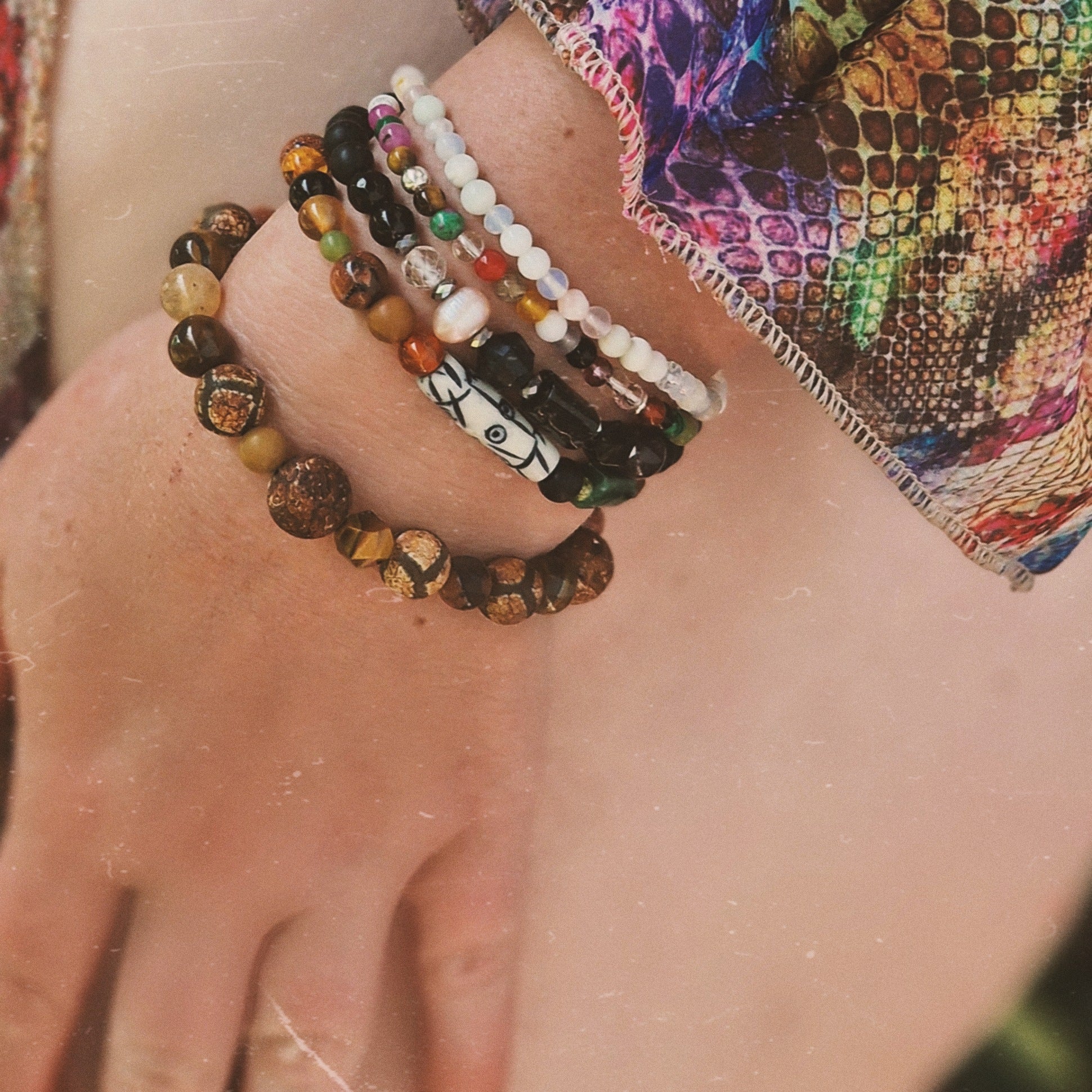 Close-up of a woman’s wrist adorned with the Anri Zenya Pearl & Crystal Whisper bracelet, featuring mother-of-pearl, agate, howlite, and clear quartz beads against a flowing silk dress