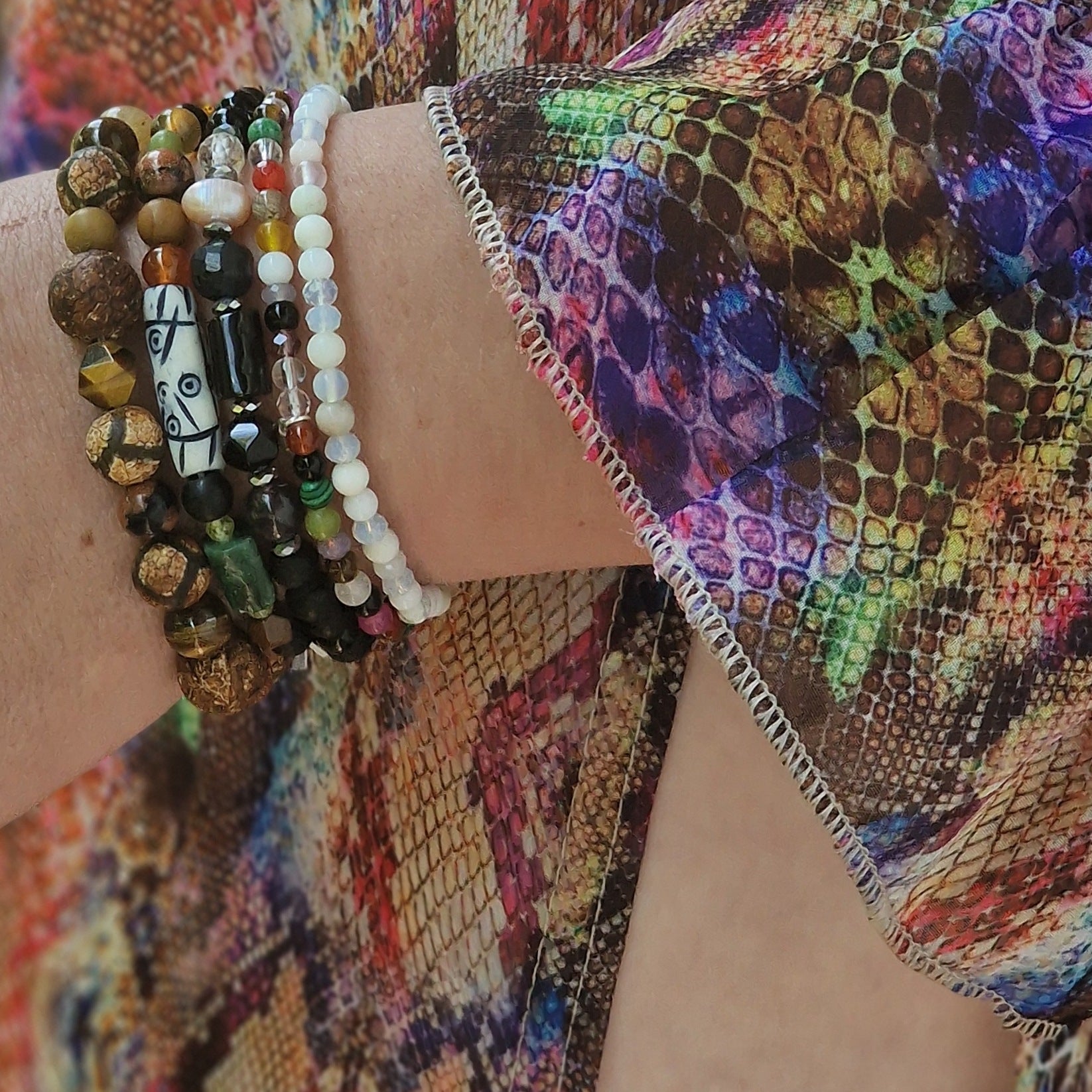 Woman’s wrist in evening gown featuring the Earth’s Waterfall bracelet with African agates, sunstone, tiger’s eye and jasper mix in earthy hues