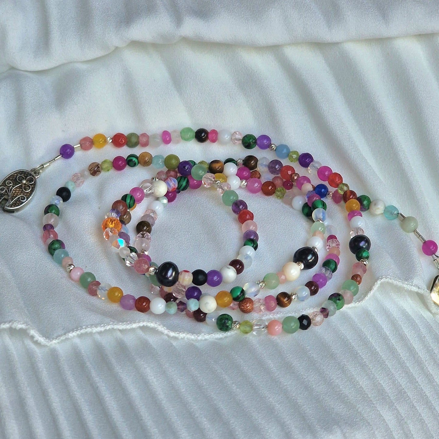 A versatile 5-wrap crystal energy bracelet on a woman’s wrist, showcasing Madagascar jadeite, amethyst, moonstone, agate and howlite beads