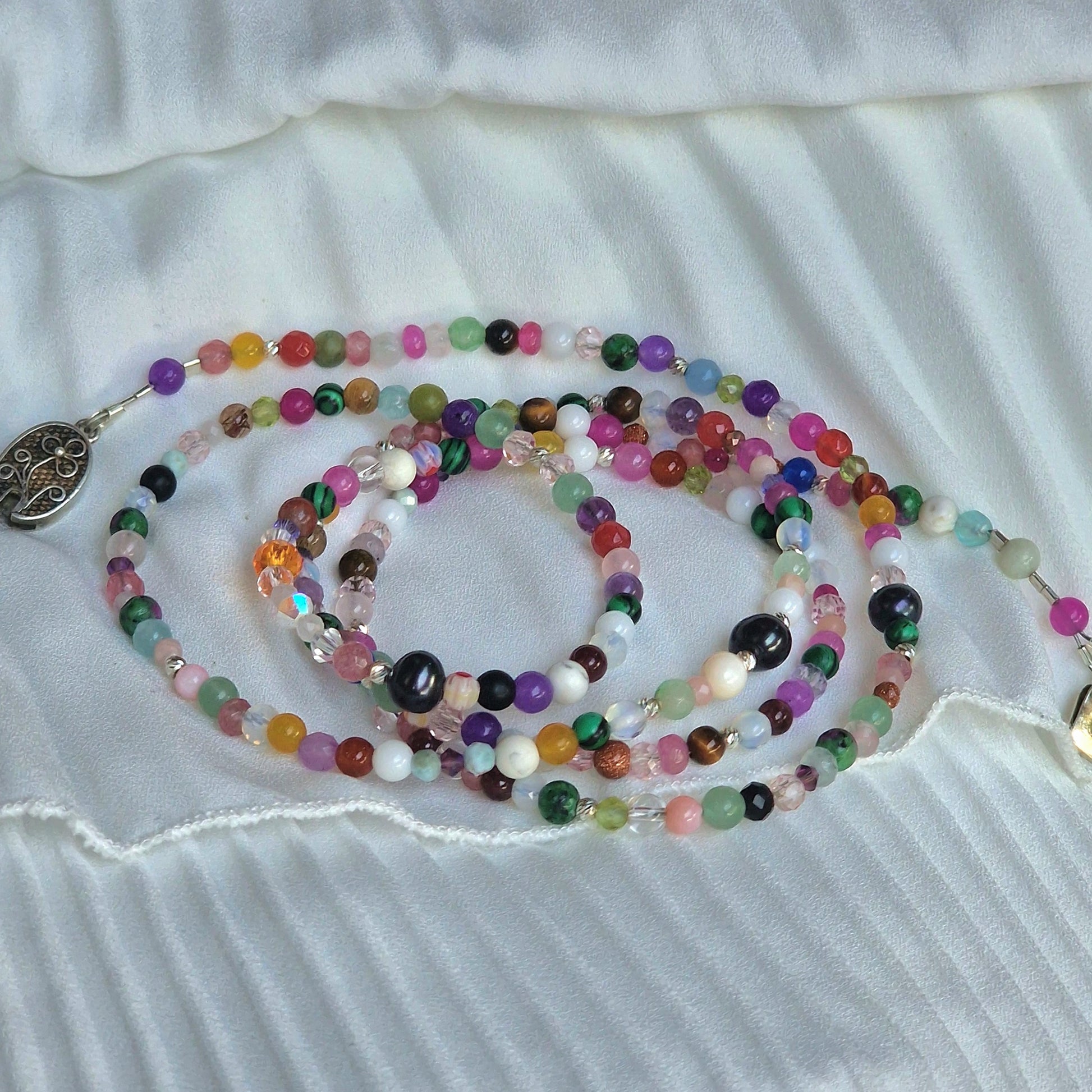 A versatile 5-wrap crystal energy bracelet on a woman’s wrist, showcasing Madagascar jadeite, amethyst, moonstone, agate and howlite beads